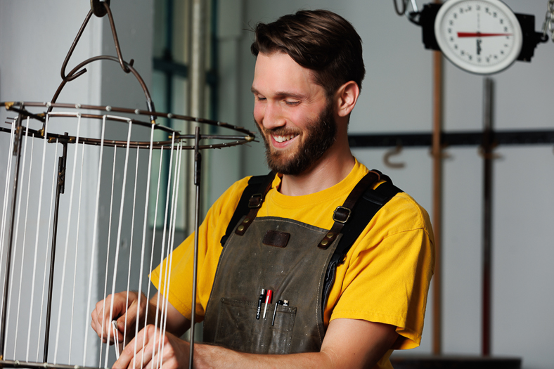 Waxman's head candle maker, Mitch, stands wicking a taper rack in Waxman's candle studio.