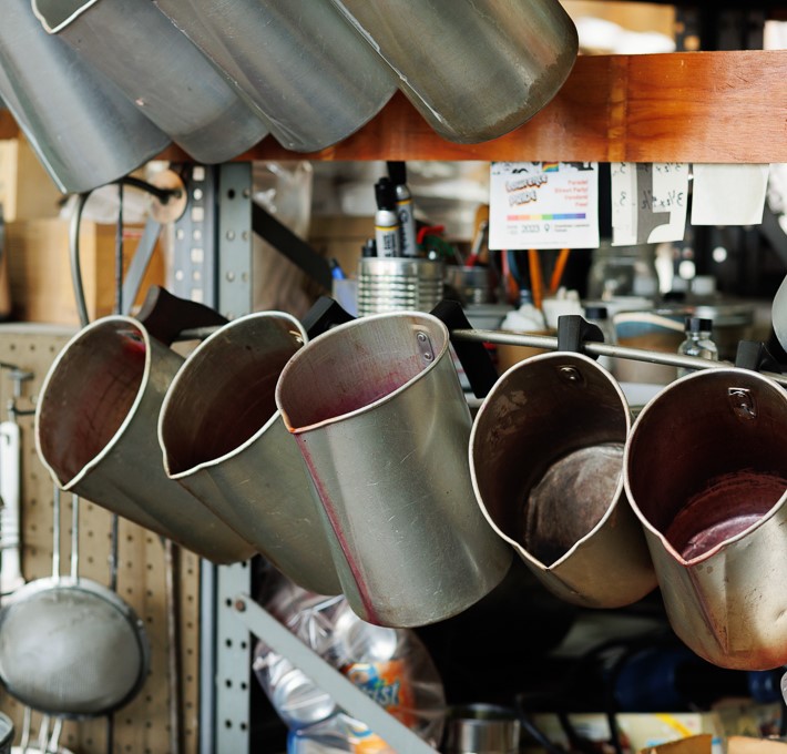 Silver metal wax pitchers hanging on a rack in Waxman's studio.